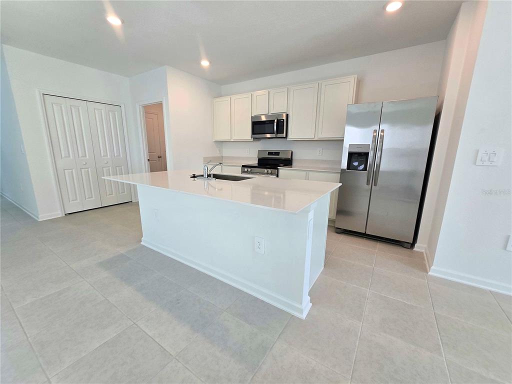 A kitchen features white cabinets, stainless steel appliances, a center island, and tile flooring — 2733 LOOKOUT RIDGE ROAD, HAINES CITY, FL