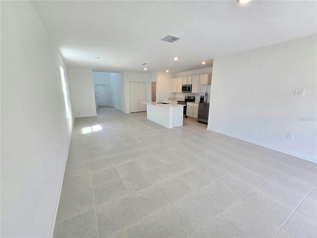 An open-concept kitchen and living area features white cabinetry, a central island, and tile flooring — 2733 LOOKOUT RIDGE ROAD, HAINES CITY, FL