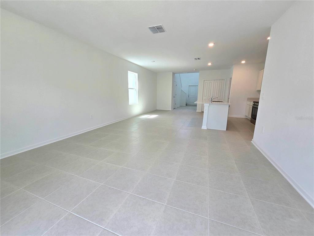 An open-concept living area features light-colored tile flooring, white walls, and a kitchen island — 2733 LOOKOUT RIDGE ROAD, HAINES CITY, FL