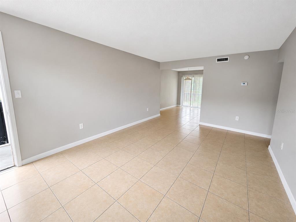 An empty room features light-colored tile flooring, gray walls, and a sliding glass door — 2779 L B MCLEOD ROAD, ORLANDO, FL