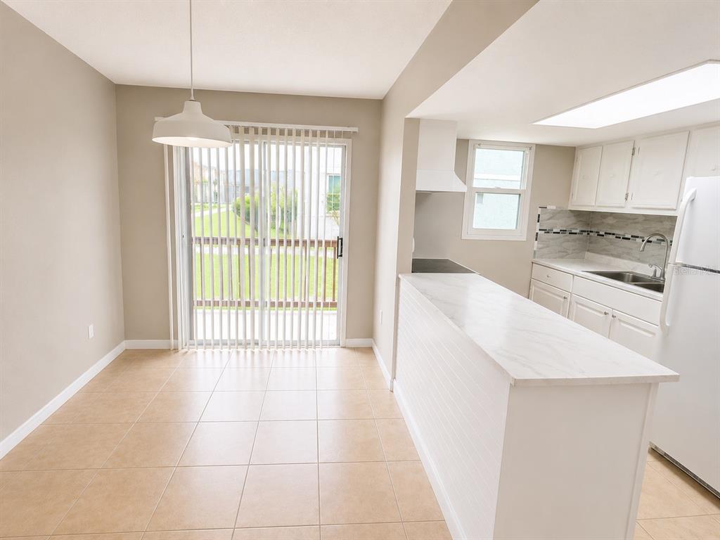 A kitchen with white cabinets and a breakfast bar opens to a dining area — 2779 L B MCLEOD ROAD, ORLANDO, FL