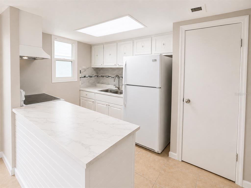 A kitchen features white cabinets, a white refrigerator, a marble-look countertop, and tile flooring — 2779 L B MCLEOD ROAD, ORLANDO, FL