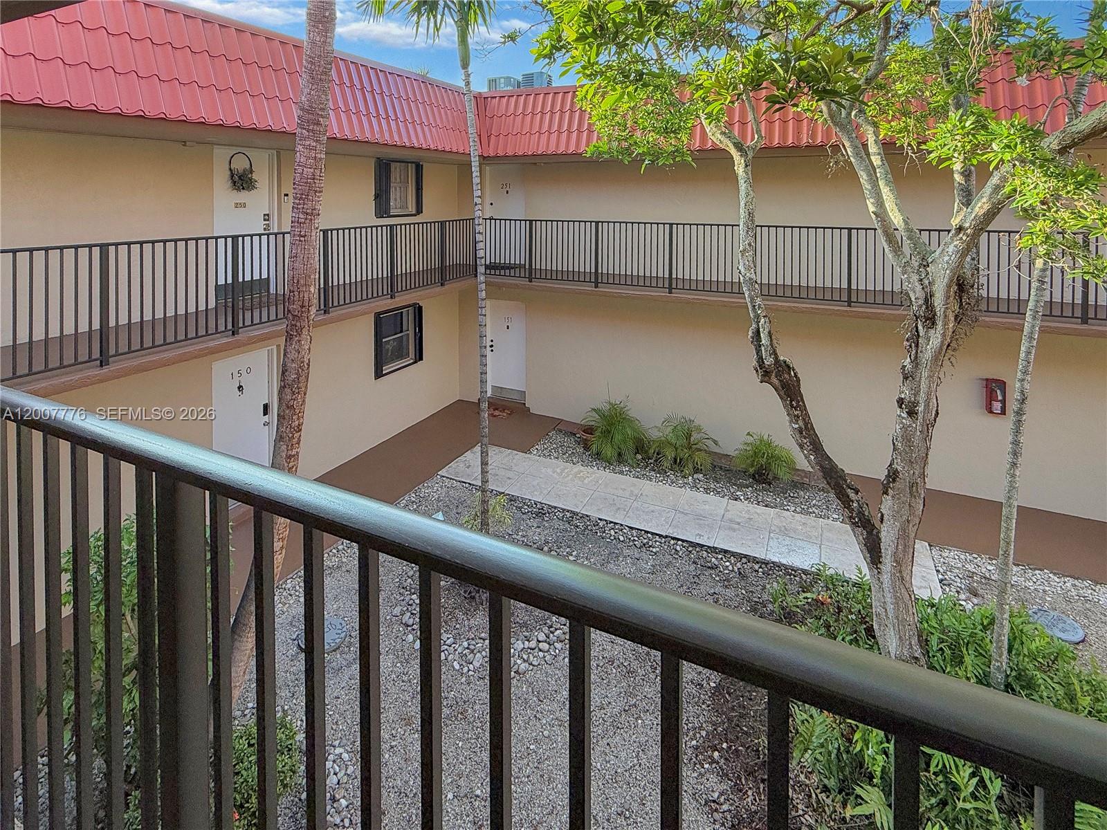 An exterior view of a two-story apartment building with balconies and a central courtyard — 10411 SW 108th Ave # 251, Miami FL 33176, MIAMI, FL
