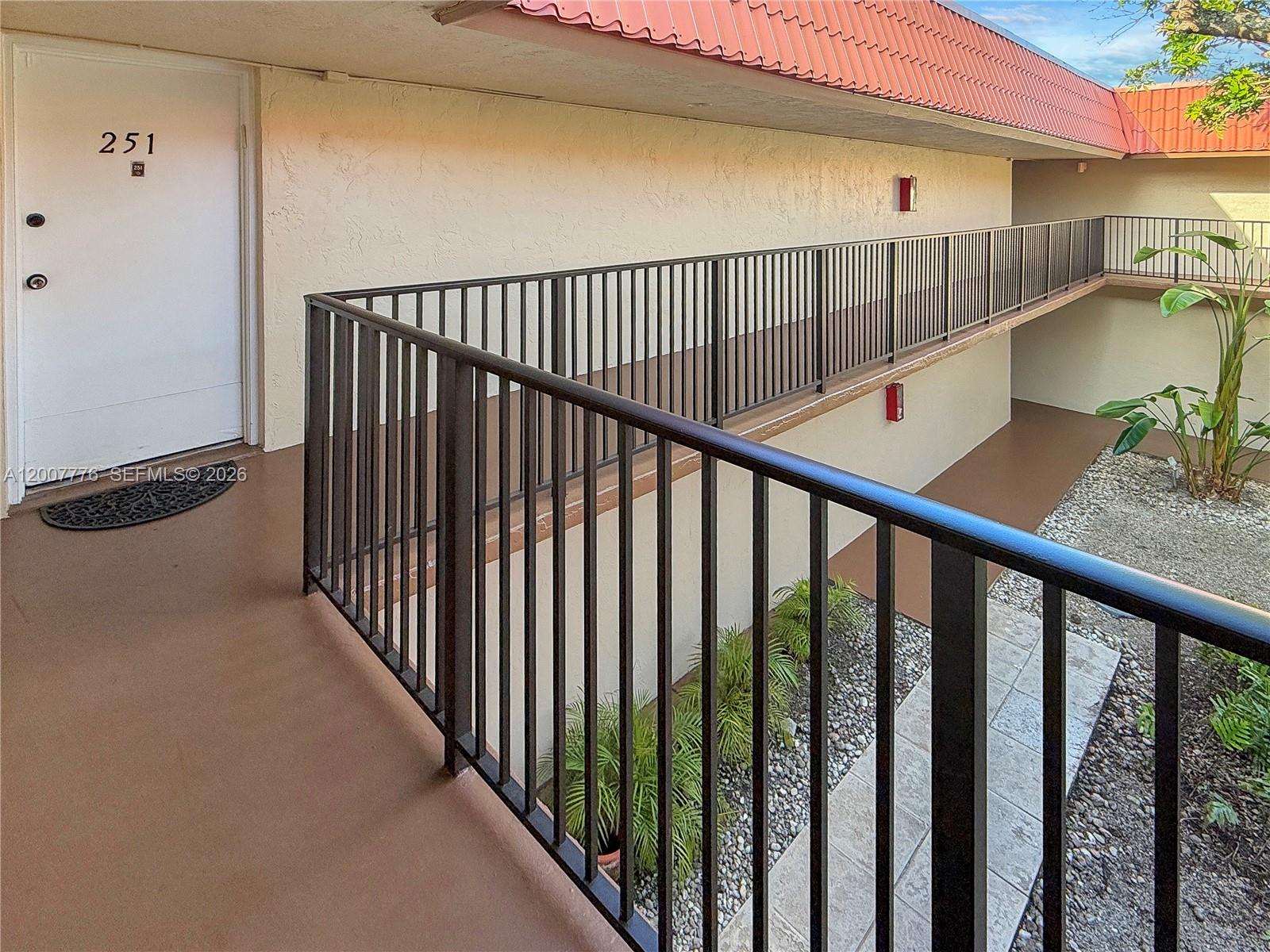 An exterior walkway with black metal railings leads to a white apartment door numbered 251 — 10411 SW 108th Ave # 251, Miami FL 33176, MIAMI, FL