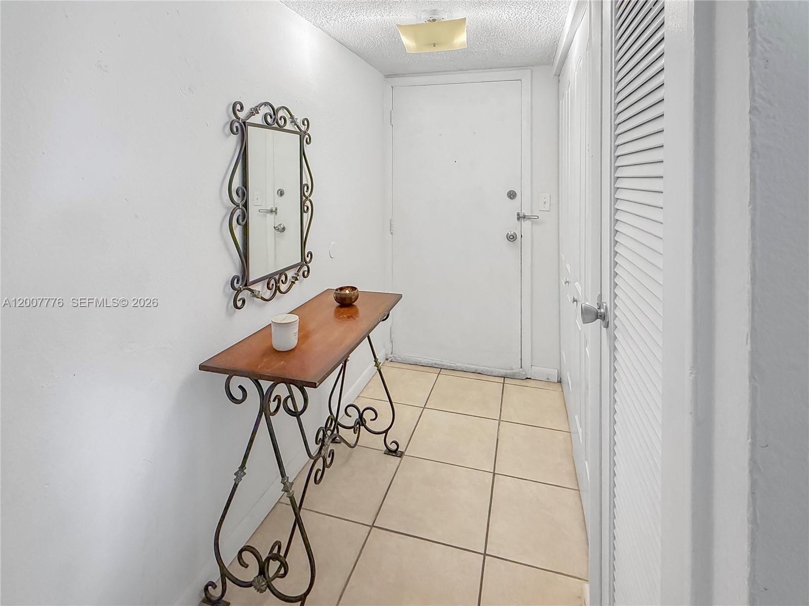 A narrow entryway features a console table, a wall mirror, and tiled flooring — 10411 SW 108th Ave # 251, Miami FL 33176, MIAMI, FL