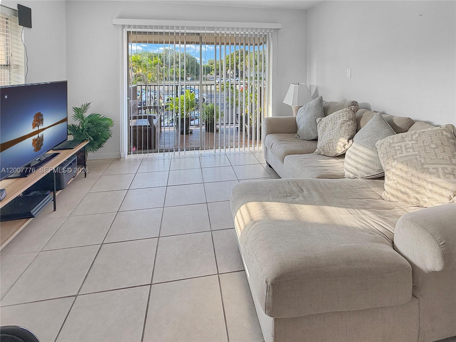 A living room features a beige sectional sofa, a television on a stand, and tile flooring — 10411 SW 108th Ave # 251, Miami FL 33176, MIAMI, FL
