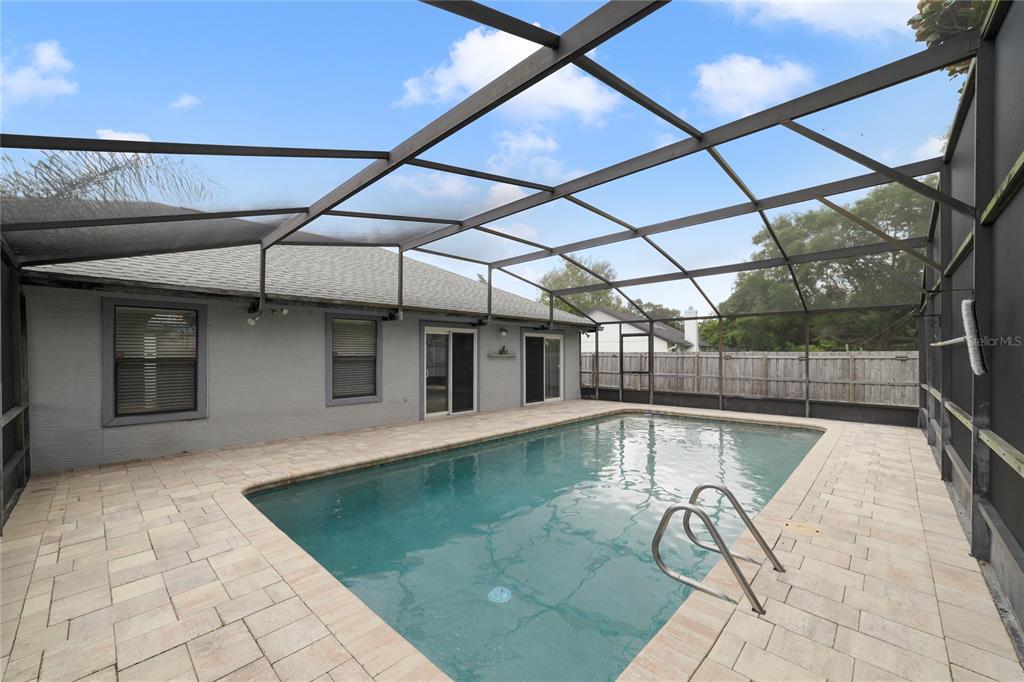 A swimming pool with a metal-framed screen enclosure sits on a paved patio — 515 STILLWATER DRIVE, OVIEDO, FL