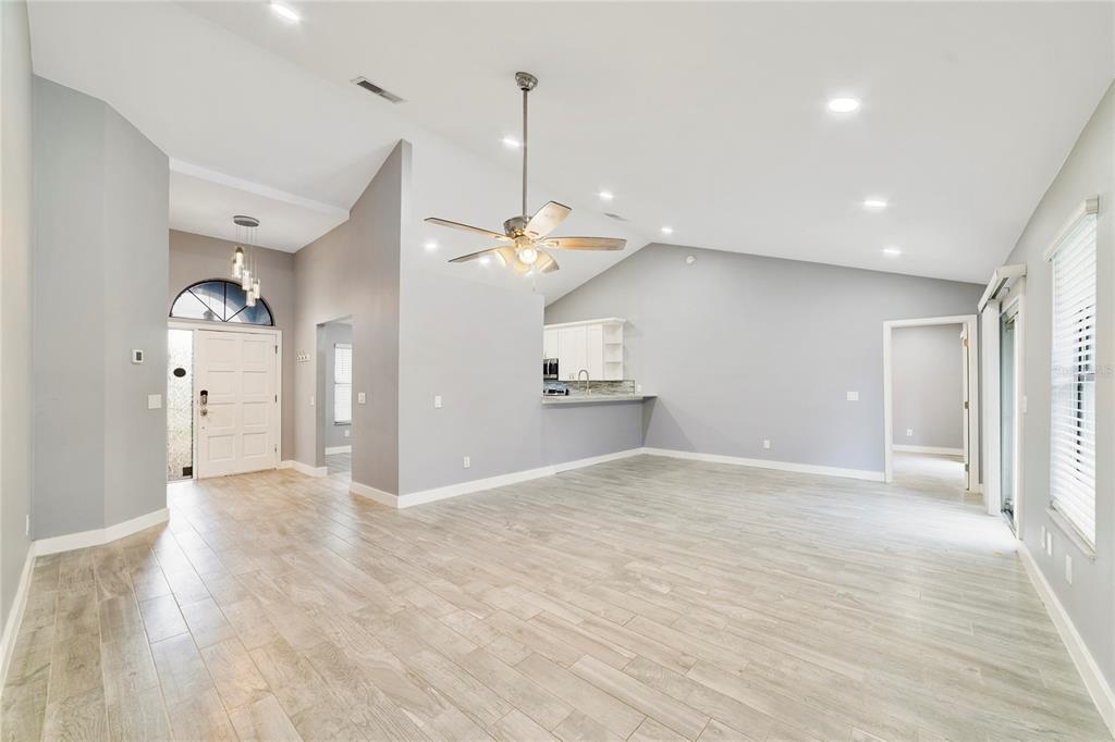 A spacious living area features light gray walls, wood-look tile flooring, and a vaulted ceiling — 515 STILLWATER DRIVE, OVIEDO, FL