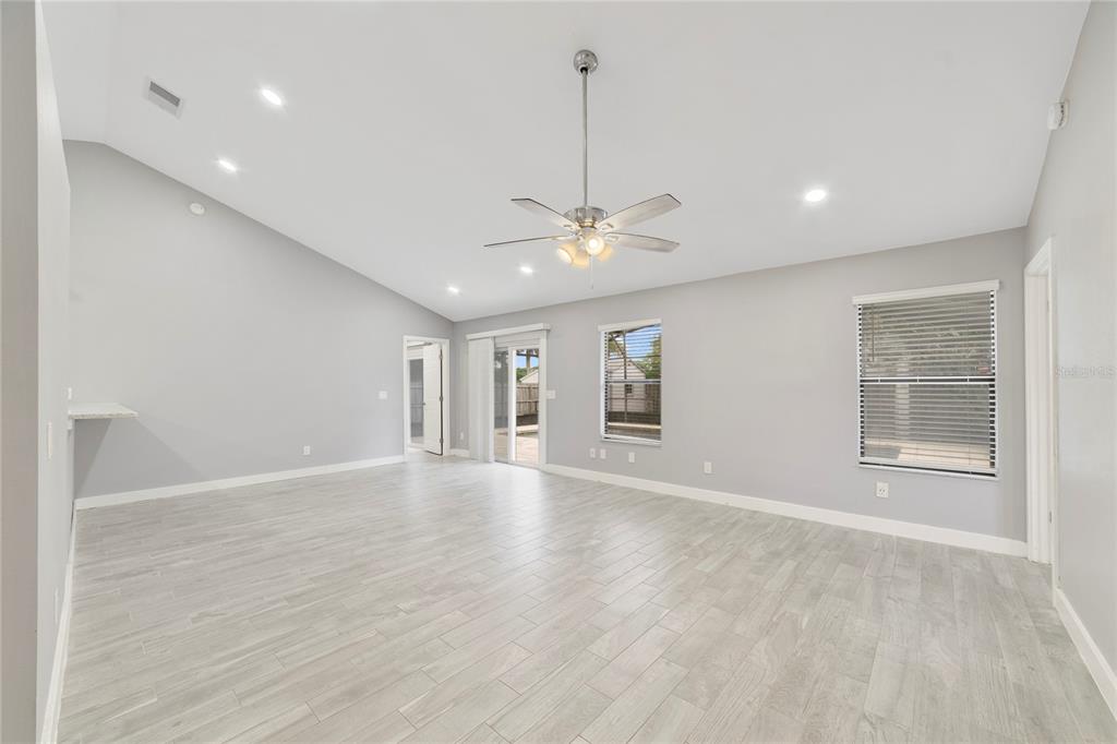 A spacious living room features light gray walls, wood-look tile flooring, and a vaulted ceiling — 515 STILLWATER DRIVE, OVIEDO, FL