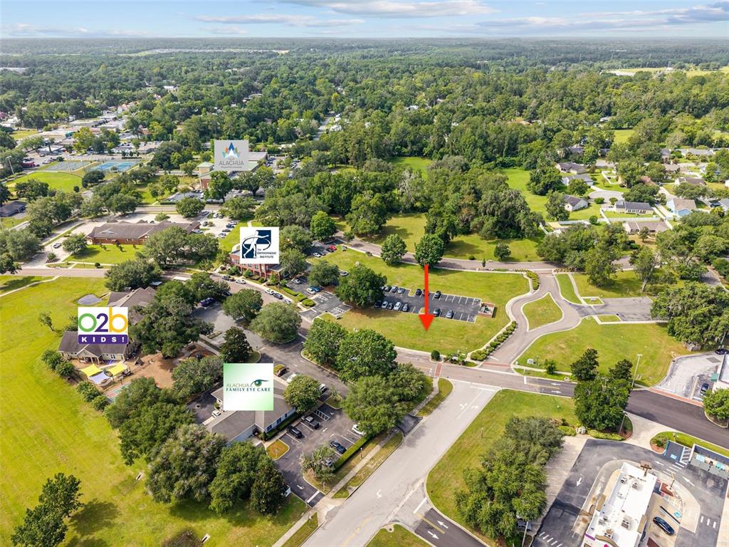 This aerial view shows a vacant commercial lot surrounded by existing buildings and parking areas — 14485 NW 152ND LANE, ALACHUA, FL