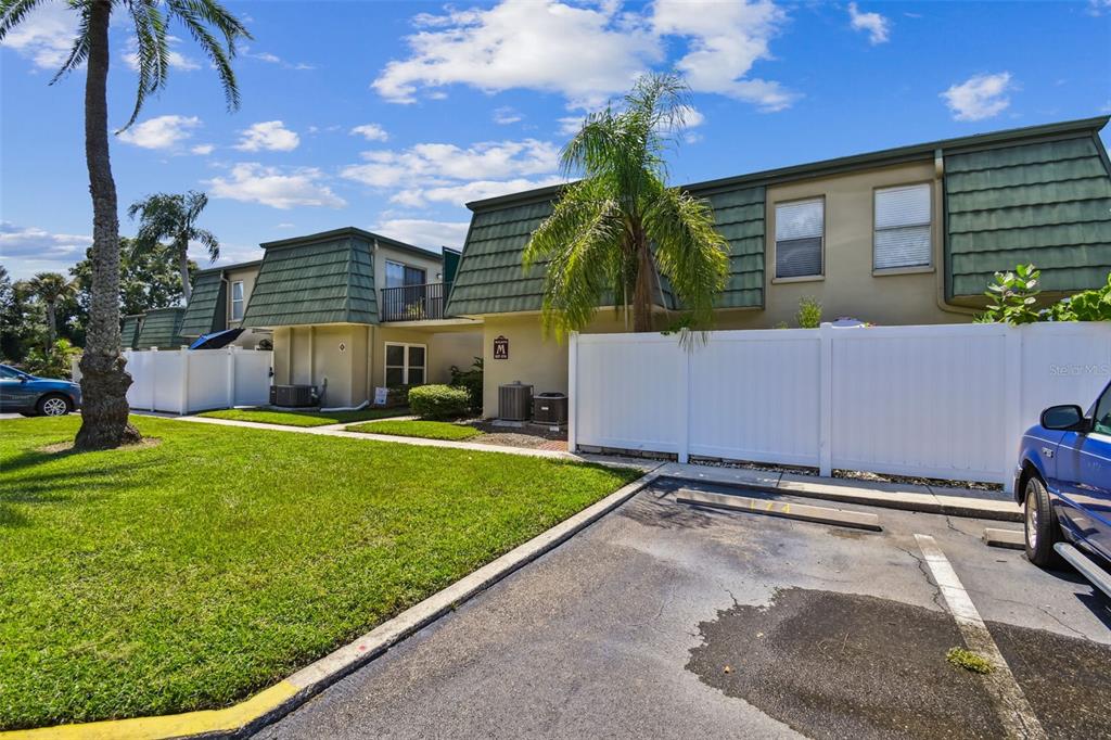 Exterior view of a two-story apartment building with green mansard roofs and white privacy fences — 1799 N HIGHLAND AVENUE UNIT 169, CLEARWATER, FL