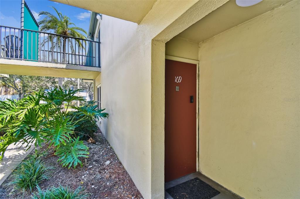 An exterior view of a building entrance with a red door numbered 169 — 1799 N HIGHLAND AVENUE UNIT 169, CLEARWATER, FL