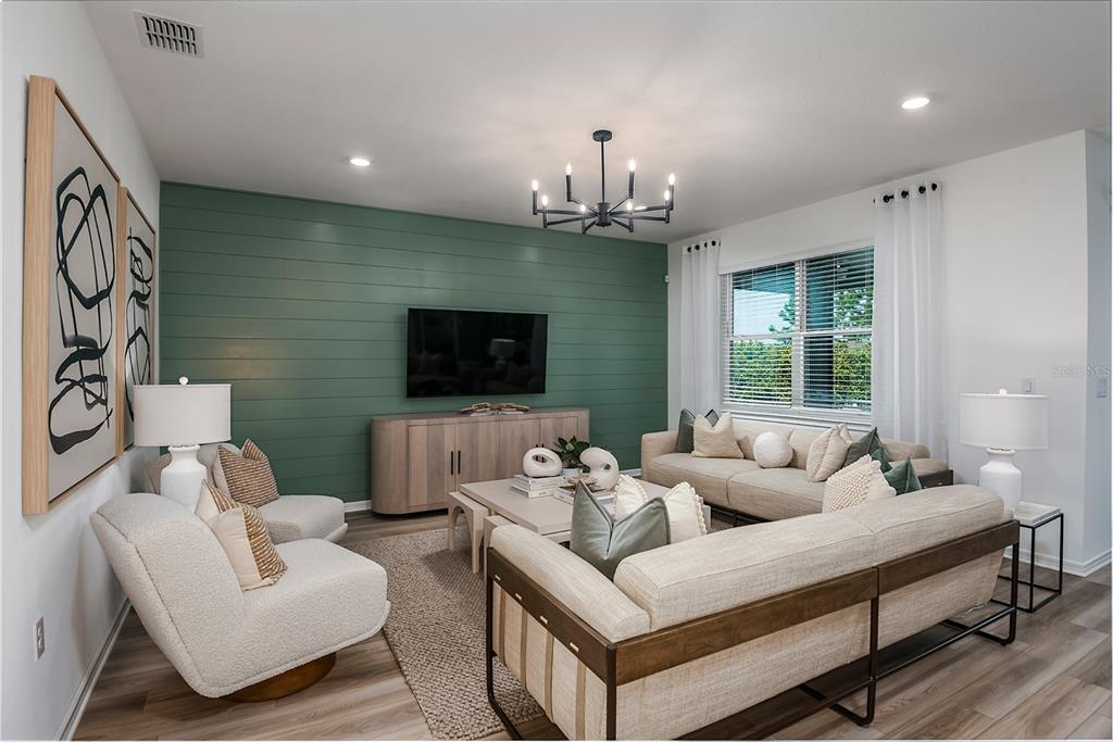 A living room features a green shiplap accent wall, a television, and neutral-toned furniture — 3663 OBSIDIAN DRIVE, SPRING HILL, FL
