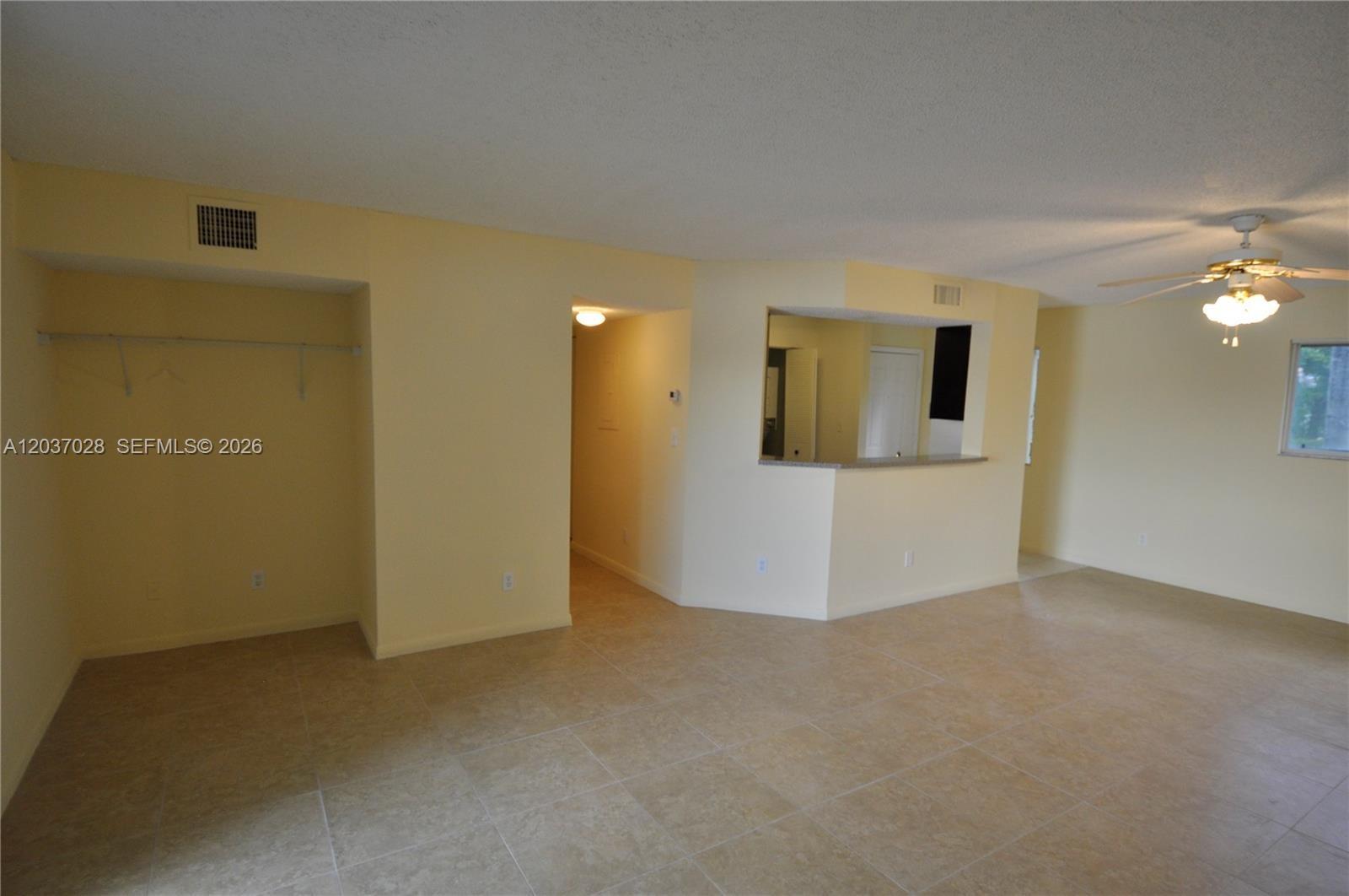 An open-concept living area features light-colored tile flooring, pale yellow walls, and a ceiling fan — 3473 NW 44th St # 103, Oakland Park FL 33309, OAKLAND PARK, FL