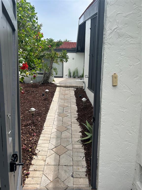 A paved walkway leads through a landscaped courtyard toward the entrance of a white house — 780 SARABAY ROAD UNIT 16, OSPREY, FL