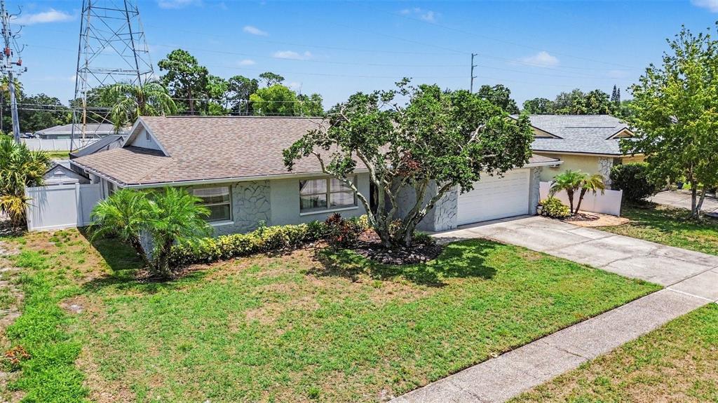 An exterior view of a single-story house with a stone facade, lawn, and driveway — 3369 HUNT CLUB DRIVE, CLEARWATER, FL