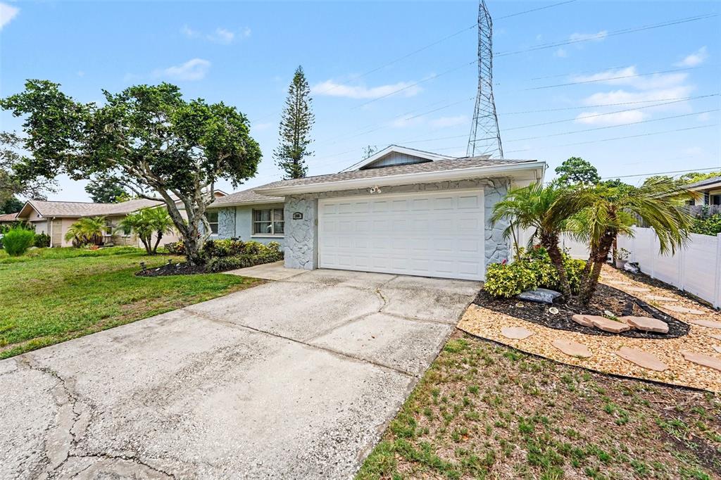 A single-story house with a white garage door, stone facade, and a concrete driveway — 3369 HUNT CLUB DRIVE, CLEARWATER, FL