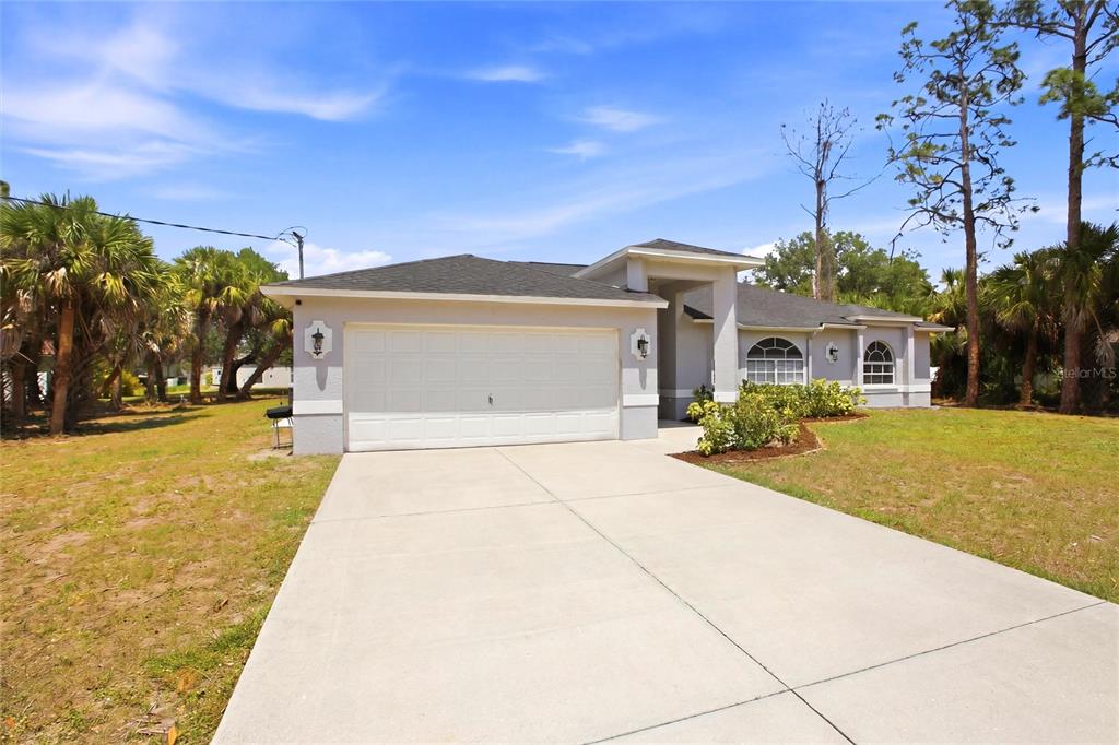 A single-story house with a two-car garage and a concrete driveway under a blue sky — 2510 SHEILA LANE, NORTH PORT, FL