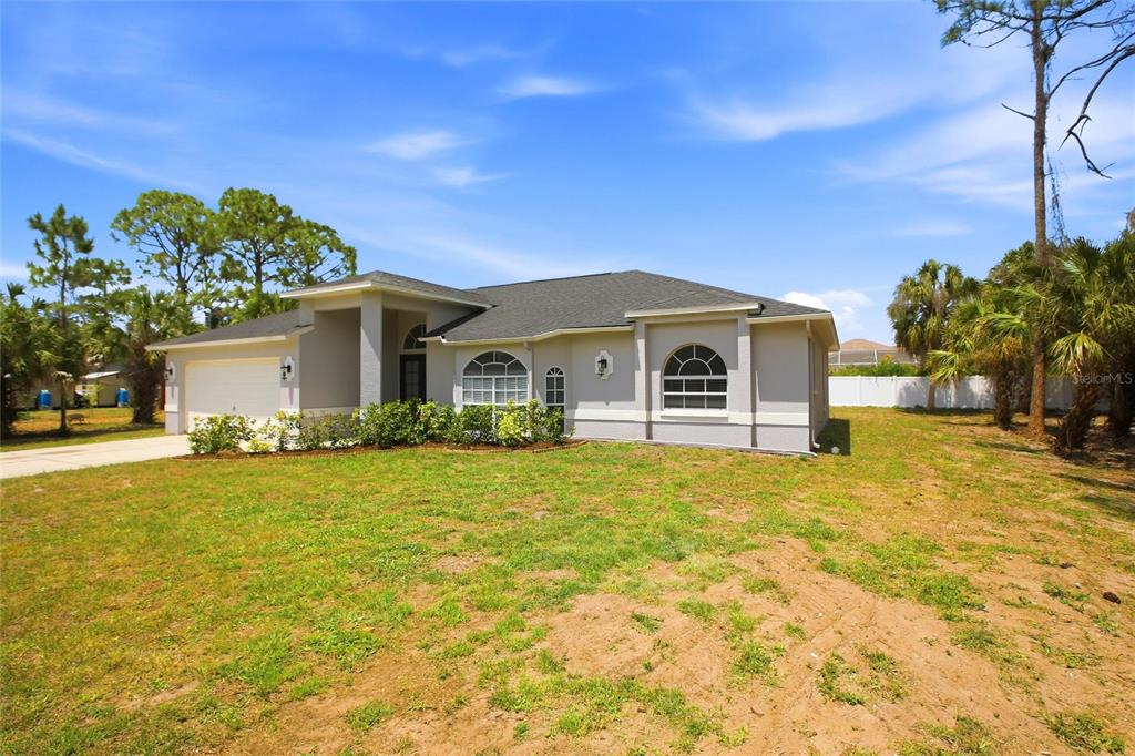 A single-story house with a light gray exterior, a two-car garage, and arched windows — 2510 SHEILA LANE, NORTH PORT, FL