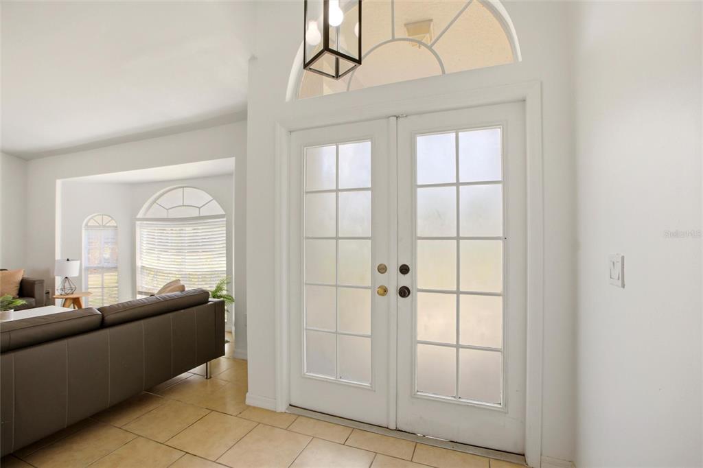A white double door entry with glass panes opens into a tiled living room area — 2510 SHEILA LANE, NORTH PORT, FL
