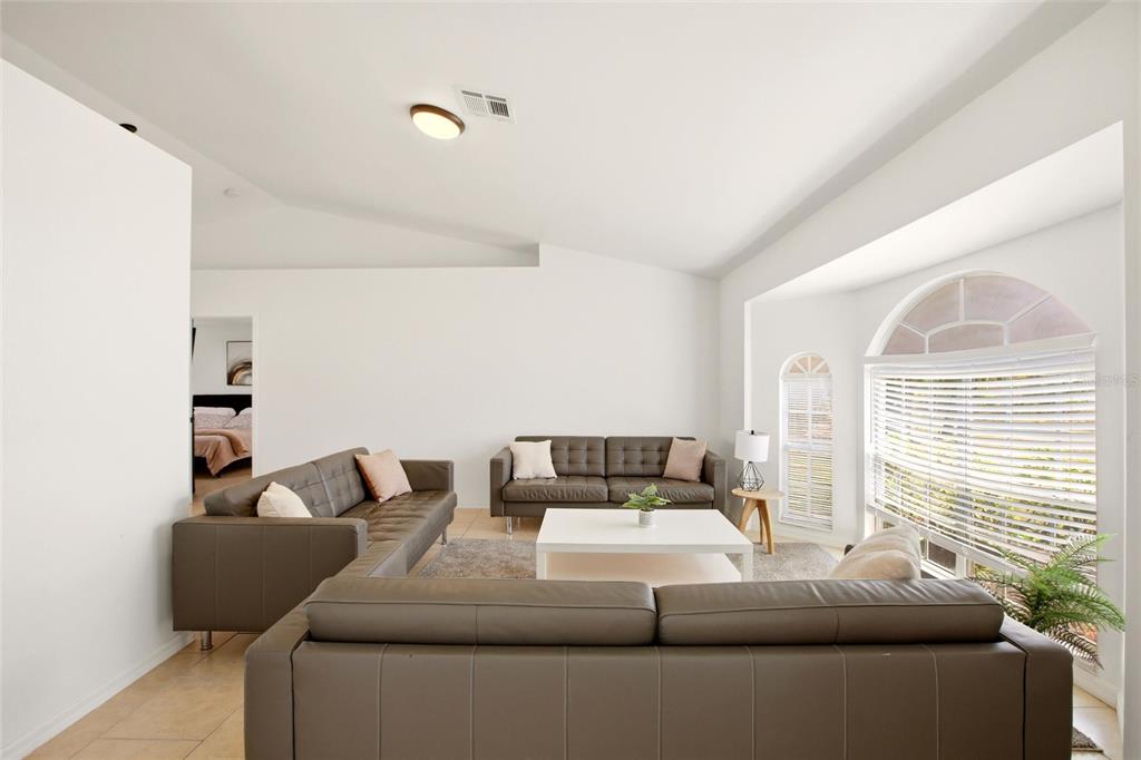A living room features a large gray sectional sofa, a white coffee table, and windows — 2510 SHEILA LANE, NORTH PORT, FL