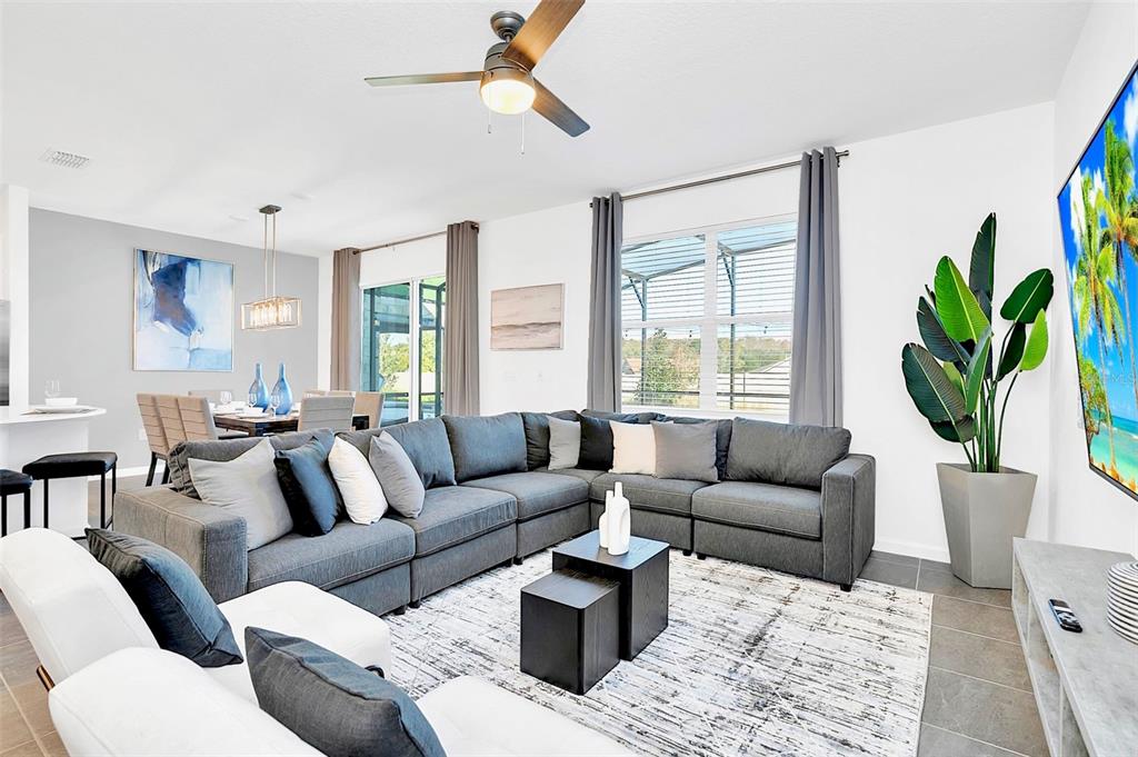 A modern living room features a large grey sectional sofa, a white rug, and a television — 234 MARCELLO BOULEVARD, KISSIMMEE, FL