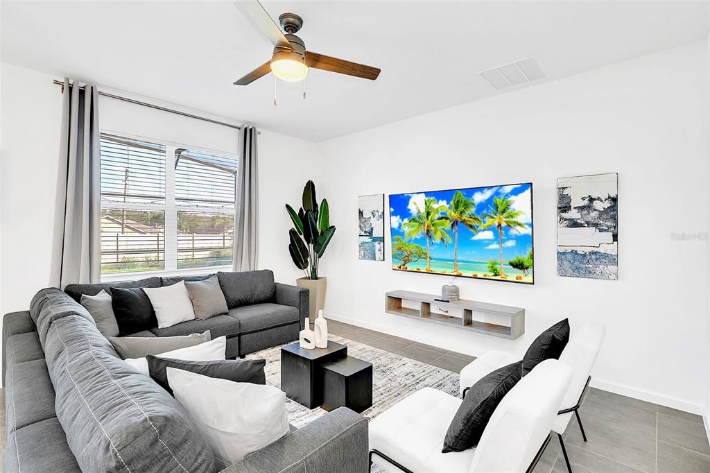 A living room features a gray sectional sofa, white chairs, a wall-mounted television, and tile flooring — 234 MARCELLO BOULEVARD, KISSIMMEE, FL