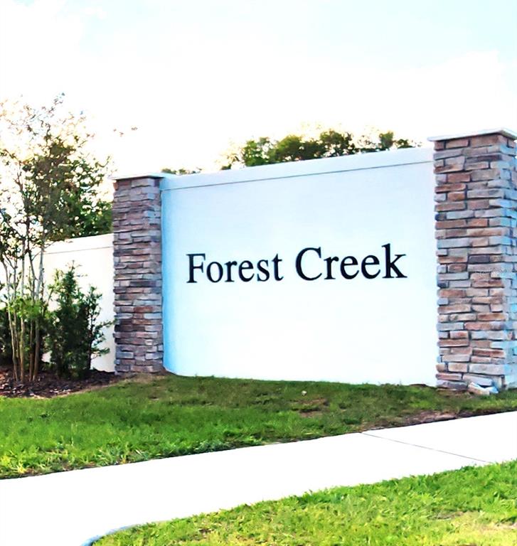 A single-story house with a beige exterior, a two-car garage, and a concrete driveway — 932 BLUE CREEK DRIVE, HAINES CITY, FL