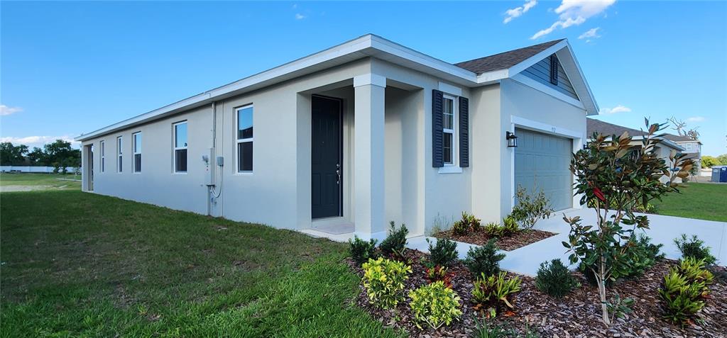 A modern kitchen with white cabinets, stainless steel appliances, and an island overlooks a backyard — 932 BLUE CREEK DRIVE, HAINES CITY, FL