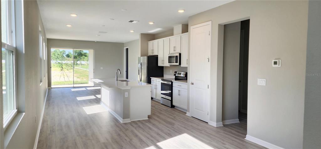 A modern kitchen features white cabinets, stainless steel appliances, and a large central island — 932 BLUE CREEK DRIVE, HAINES CITY, FL