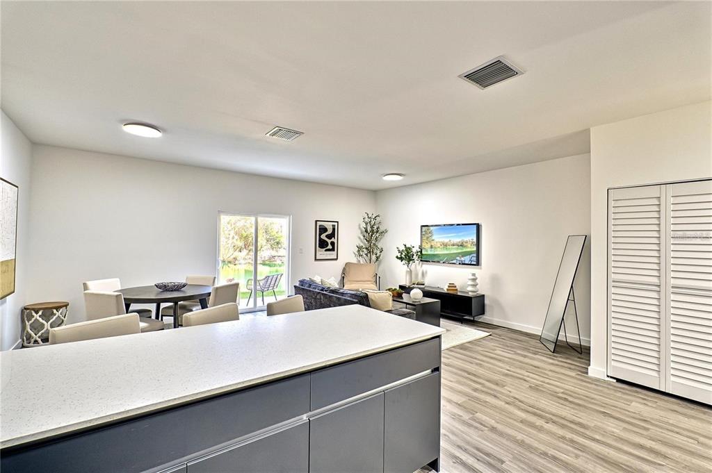 A kitchen island overlooks an open-concept living and dining area with wood-look flooring — 1595 NW 29TH ROAD UNIT 3, GAINESVILLE, FL