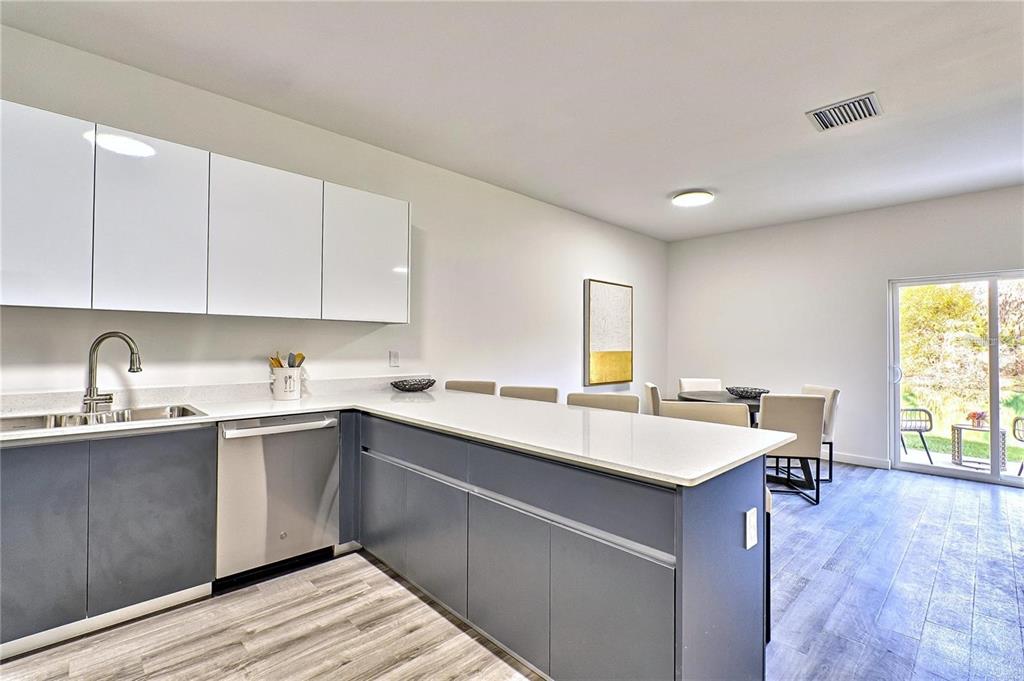 A modern kitchen features dark gray lower cabinets, white upper cabinets, and a white countertop — 1595 NW 29TH ROAD UNIT 3, GAINESVILLE, FL