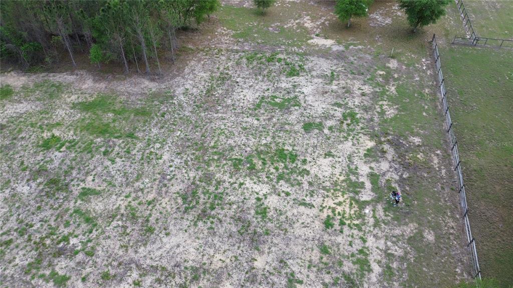 An aerial view shows a large, partially cleared grassy lot bordered by trees and fencing — 16865 SE 27TH PLACE ROAD, OCKLAWAHA, FL
