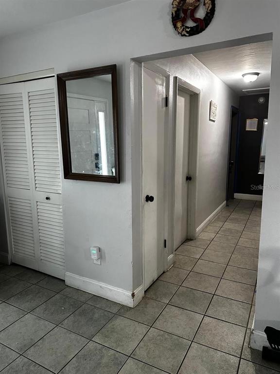 A hallway with tiled floors, white louvered closet doors, and a wall-mounted mirror — 1048 WAKEFIELD CIRCLE, DELTONA, FL