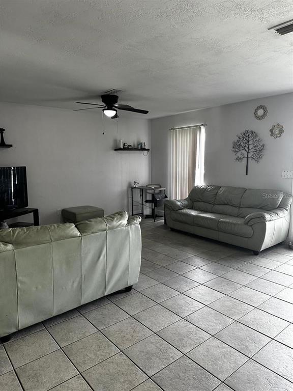 A living room features light-colored tile flooring, two sofas, and a ceiling fan — 1048 WAKEFIELD CIRCLE, DELTONA, FL