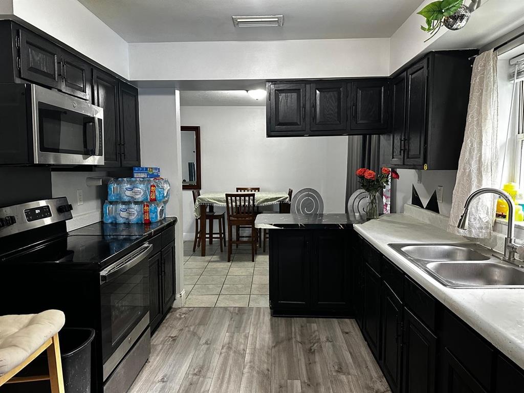 A kitchen features black cabinets, stainless steel appliances, and a view into the dining area — 1048 WAKEFIELD CIRCLE, DELTONA, FL