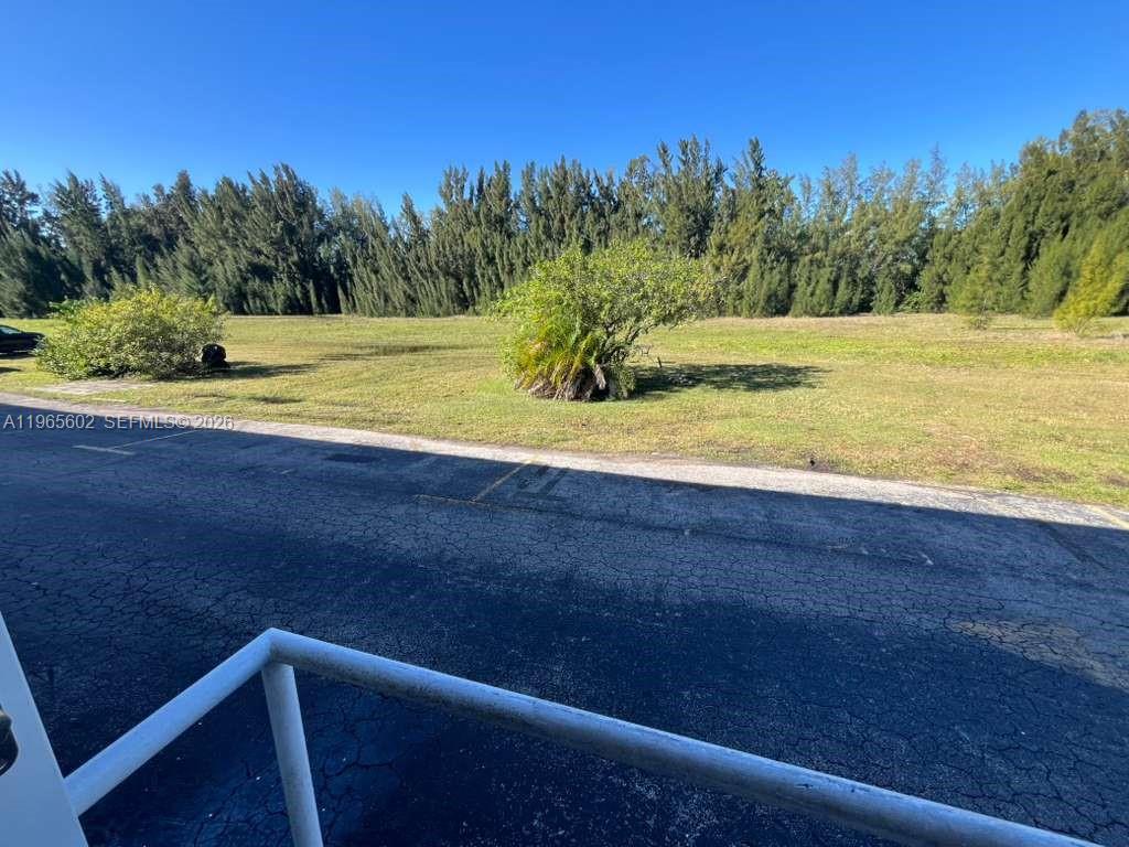 A paved parking area sits in front of a grassy field with trees — 600 Layne Blvd # 110, Hallandale Beach FL 33009, HALLANDALE BEACH, FL
