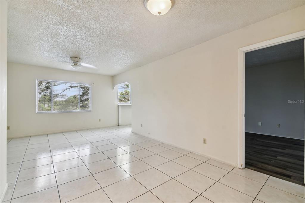 A room with white tiled floors, white walls, a ceiling fan, and an arched doorway — 645 N KEENE ROAD UNIT D, CLEARWATER, FL