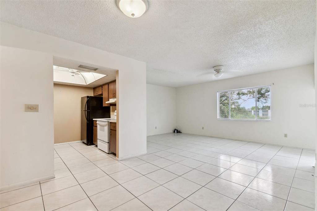 An open-concept living area with white tile flooring connects to a kitchen with dark cabinetry — 645 N KEENE ROAD UNIT D, CLEARWATER, FL
