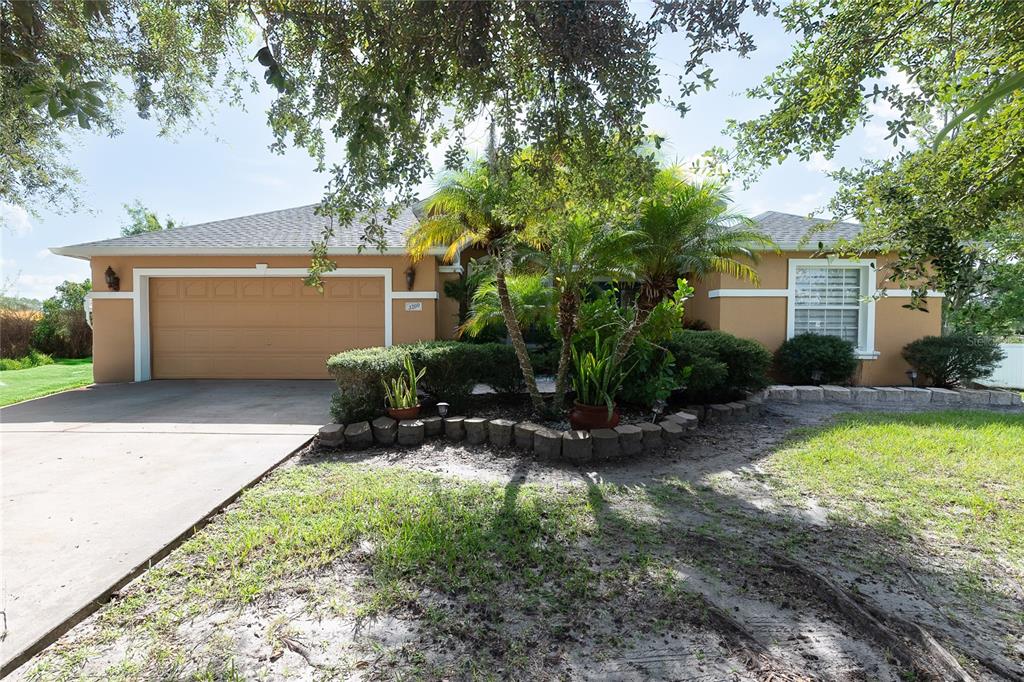 A single-story house with a tan exterior, a two-car garage, and a landscaped front yard — 3200 VICTORIA DRIVE, KISSIMMEE, FL