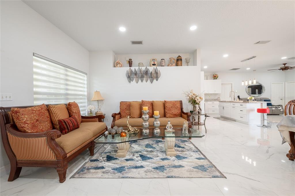 A living room features a glass coffee table, two sofas, and white marble flooring — 3200 VICTORIA DRIVE, KISSIMMEE, FL