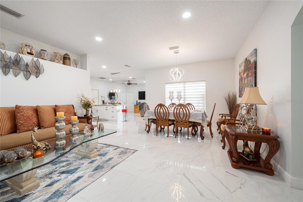 An open-concept living and dining area features white marble floors and modern light fixtures — 3200 VICTORIA DRIVE, KISSIMMEE, FL