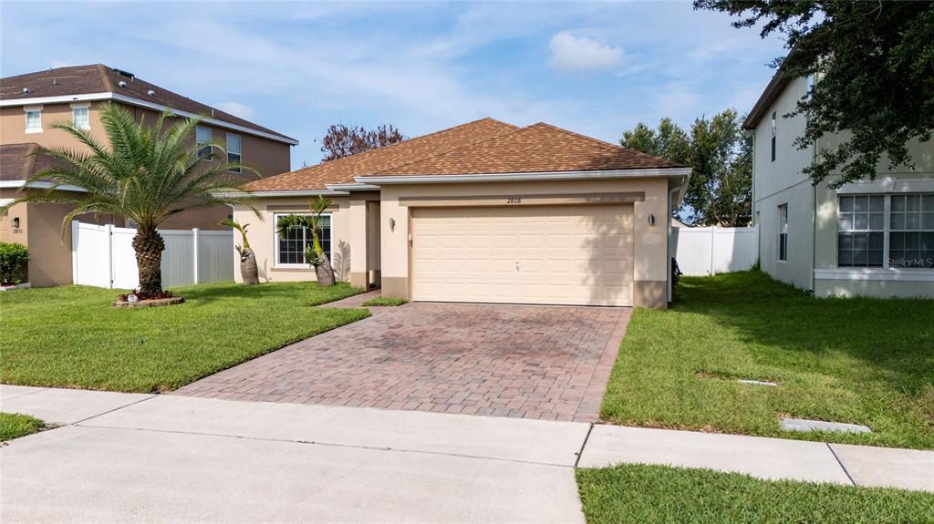 A single-story house with a tan exterior, a two-car garage, and a paved driveway — 2808 POLSON DRIVE, KISSIMMEE, FL