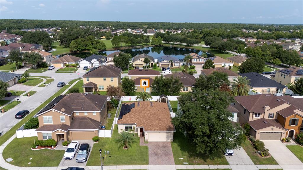 An aerial view shows a suburban neighborhood with houses, a central pond, and green spaces — 2808 POLSON DRIVE, KISSIMMEE, FL