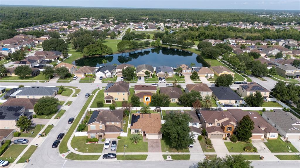An aerial view shows a suburban neighborhood with houses surrounding a central pond — 2808 POLSON DRIVE, KISSIMMEE, FL