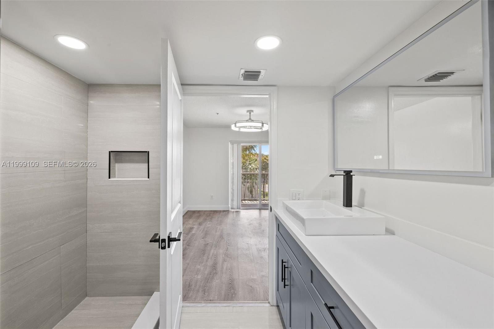 A bathroom with a walk-in shower, gray vanity, and a doorway leading to a bedroom — 470 S Park Rd # 307, Hollywood FL 33021, HOLLYWOOD, FL