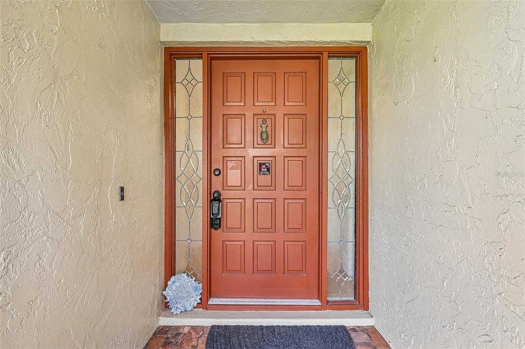 A front entryway featuring a terracotta-colored door with side windows and a textured wall finish — 632 DESOTO DRIVE UNIT 632, CASSELBERRY, FL