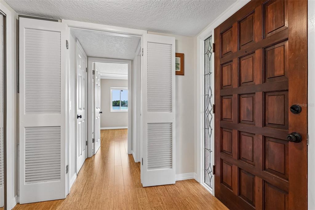 An entryway with a wooden front door, light wood flooring, and a hallway leading outside — 632 DESOTO DRIVE UNIT 632, CASSELBERRY, FL