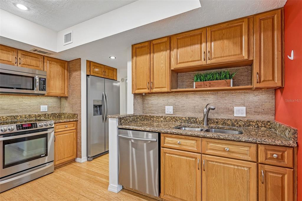 A kitchen features oak cabinets, granite countertops, stainless steel appliances, and a red accent wall — 632 DESOTO DRIVE UNIT 632, CASSELBERRY, FL