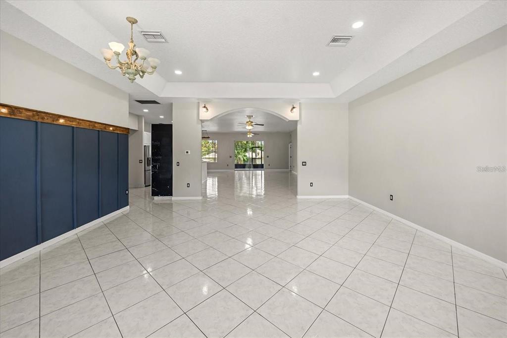 A spacious room with white tile floors, a tray ceiling, and a dark blue accent wall — 13848 VISTA DEL LAGO BOULEVARD, CLERMONT, FL